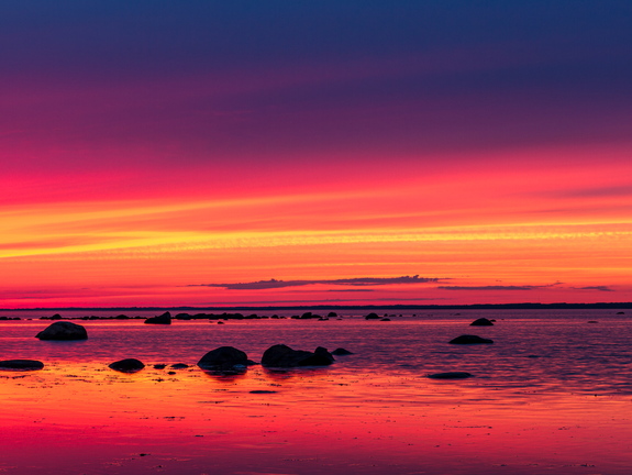 Veripunane päikeseloojang rannas panoraamina