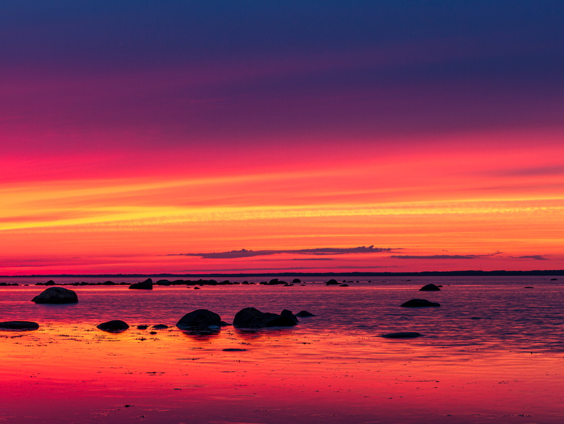 Veripunane päikeseloojang rannas panoraamina